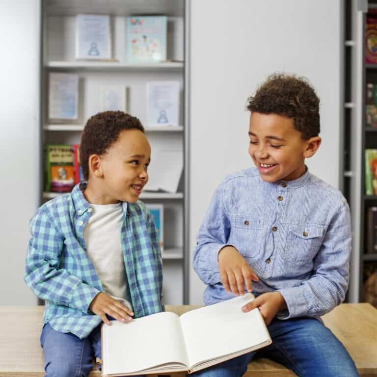 Two boys are sharing a notebook and smiling.